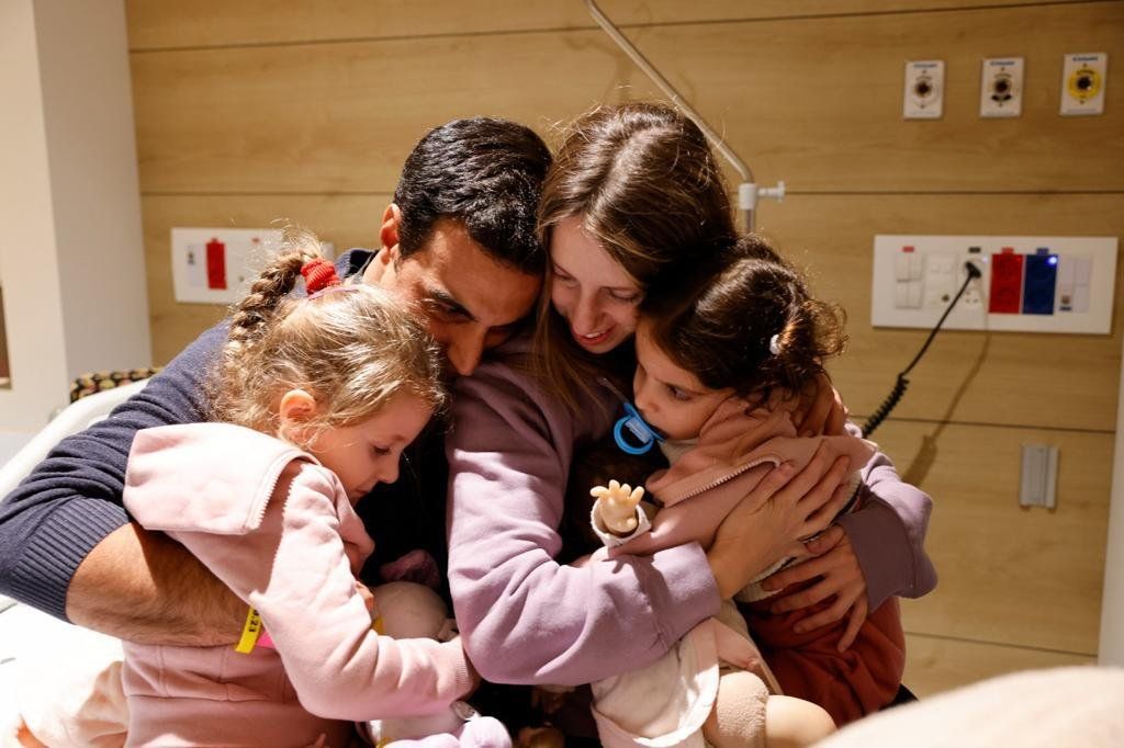 Yoni Asher embraces his wife Doron and their daughter Raz, four, and Aviv, two